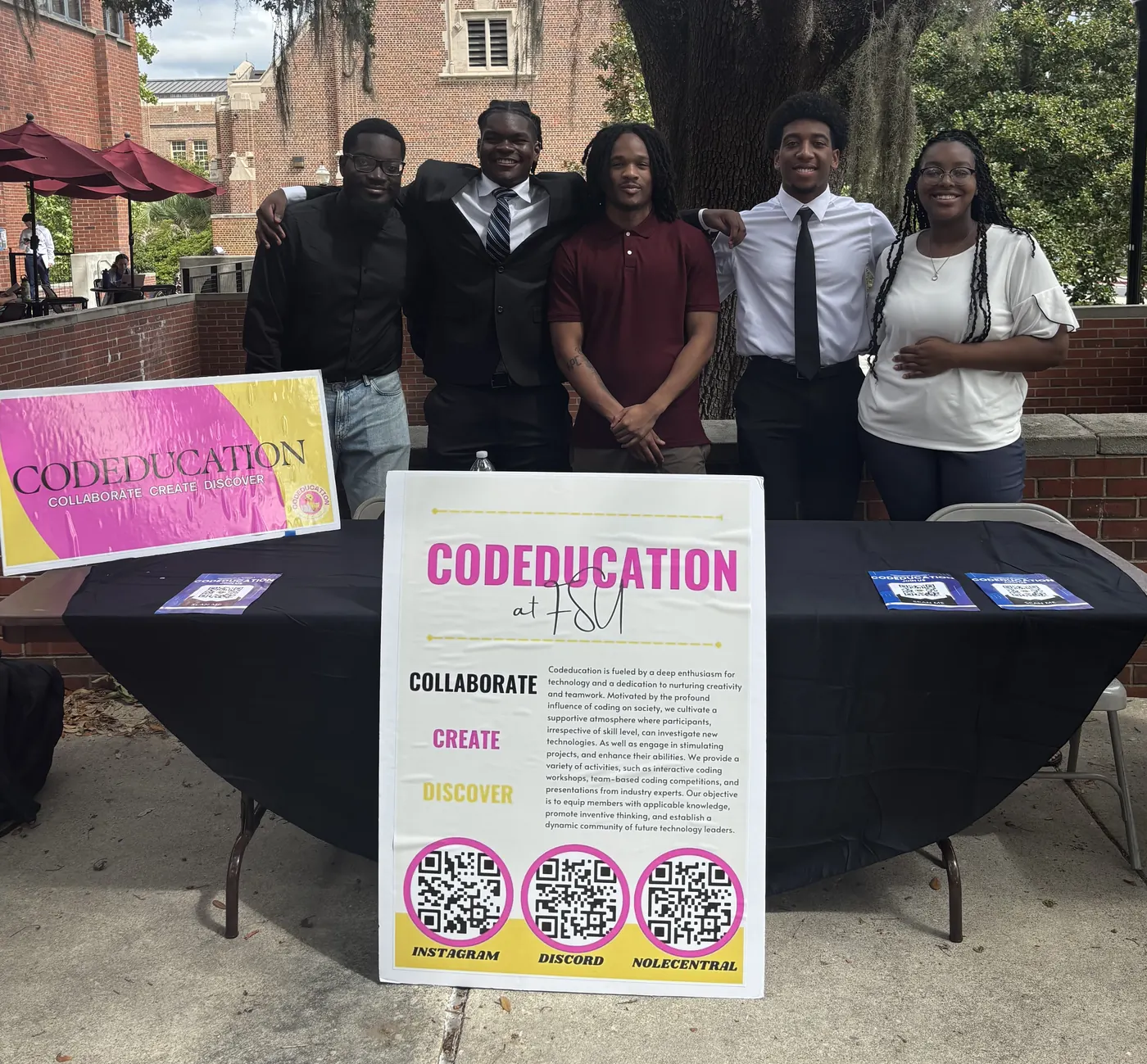 Five CodeEducation members standing behind the organization's table at Club Day